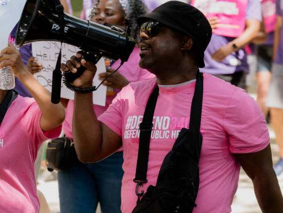 Mark Ogunsusi holding a megaphone at the March to Defend 340B